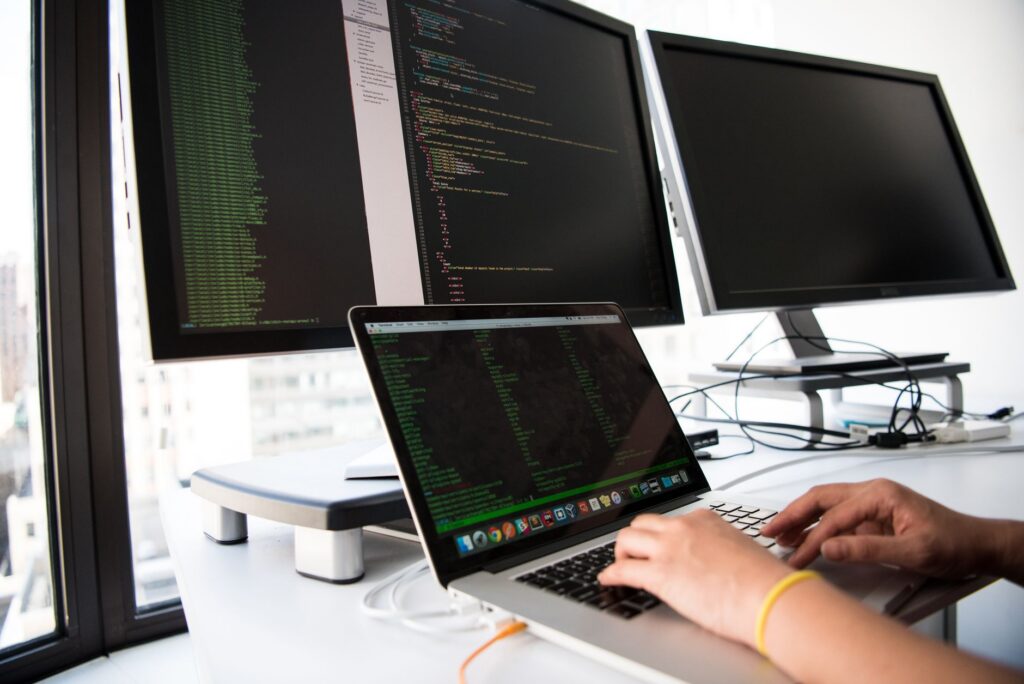 A developer works across multiple monitors and a laptop, juggling context across screens