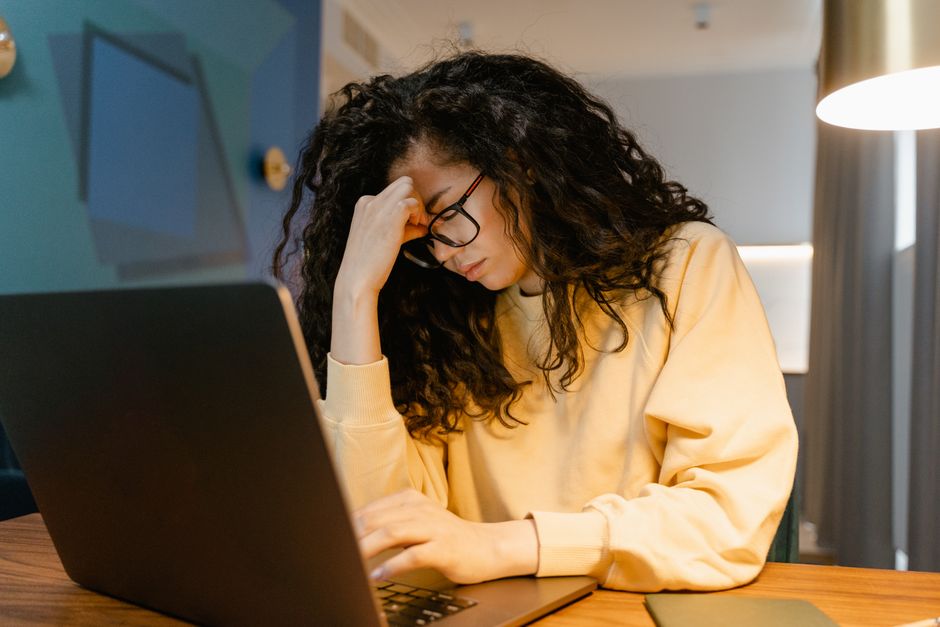 Woman looking stressed while working on a laptop