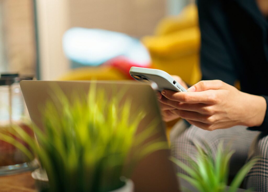 Woman multitasking on her smartphone and laptop in a living room